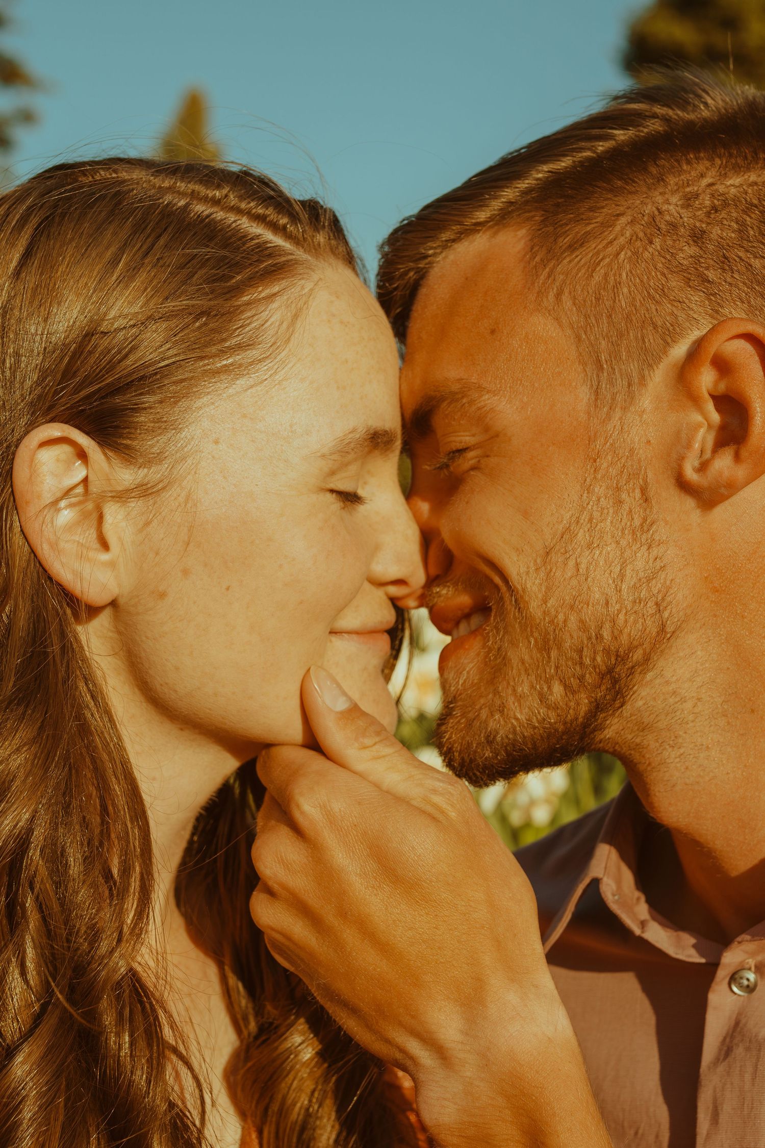 Romantic couple sharing intimate moments outdoors during golden sunset.
