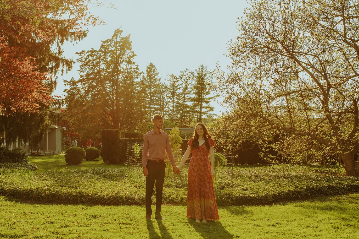 Couple embracing in a romantic outdoor autumn setting with golden sunlight filtering through trees.