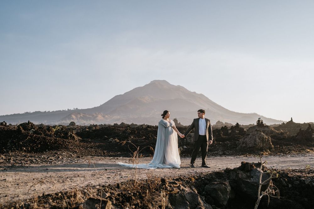 A couple in formal wear poses dramatically against a mountainous desert backdrop.