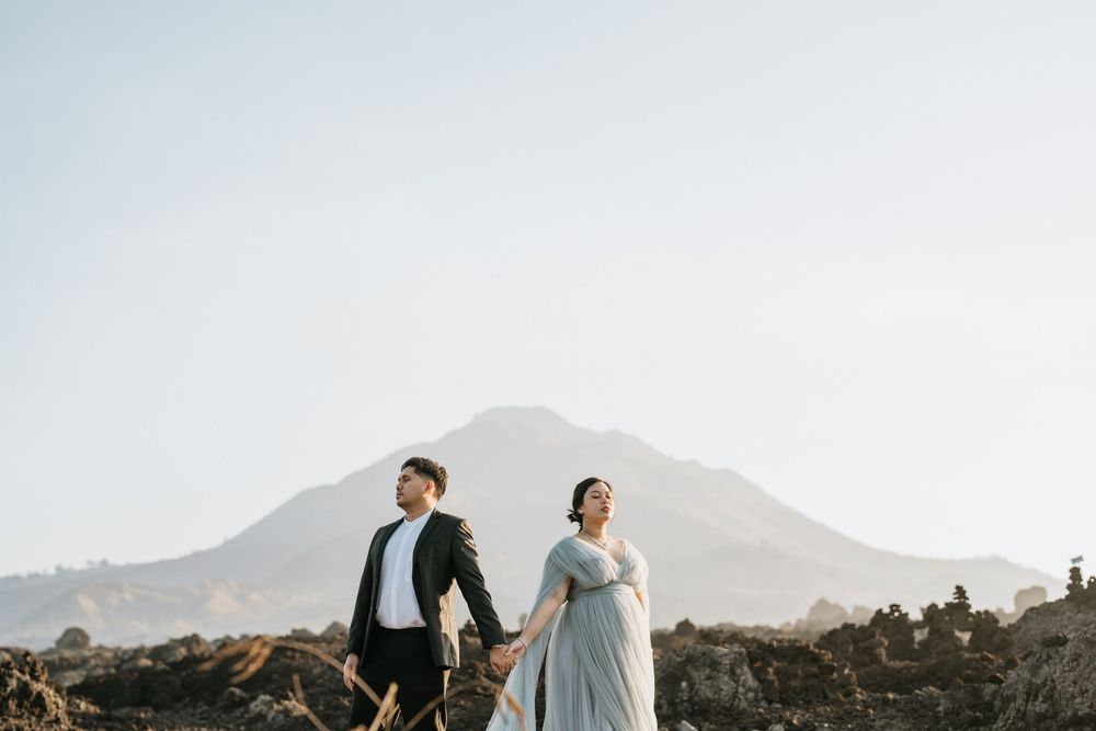 A couple poses against mountain scenery during a sunset photoshoot.