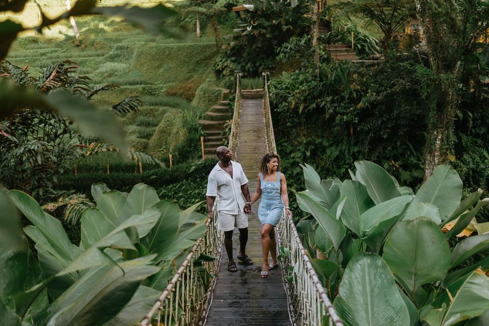 Family walking across wooden bridge surrounded by lush tropical foliage.