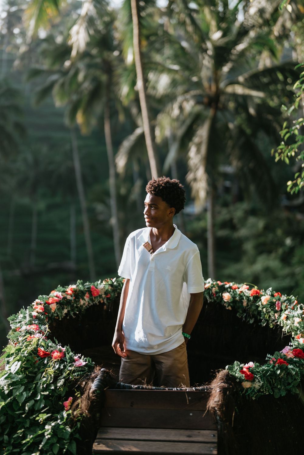A scenic portrait on a wooden deck surrounded by palm trees and tropical flowers.