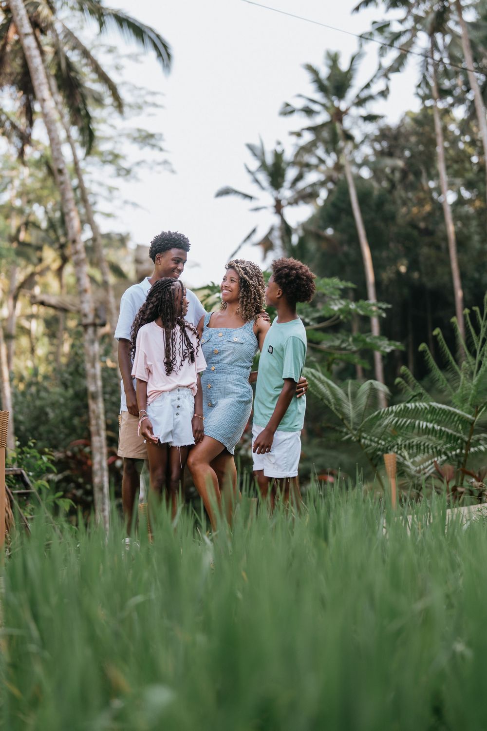 A group enjoying a moment together in tall grass with palm trees in the background.