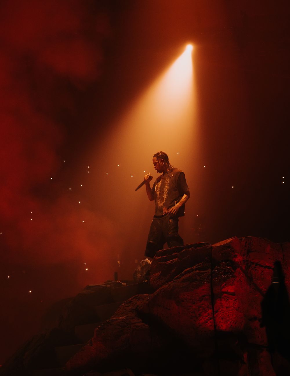 Atmospheric stage performance with red lighting and smoke creating a moody silhouette effect.