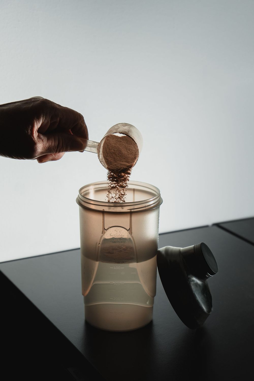A sequence showing liquid being poured into a clear container against a dark background.