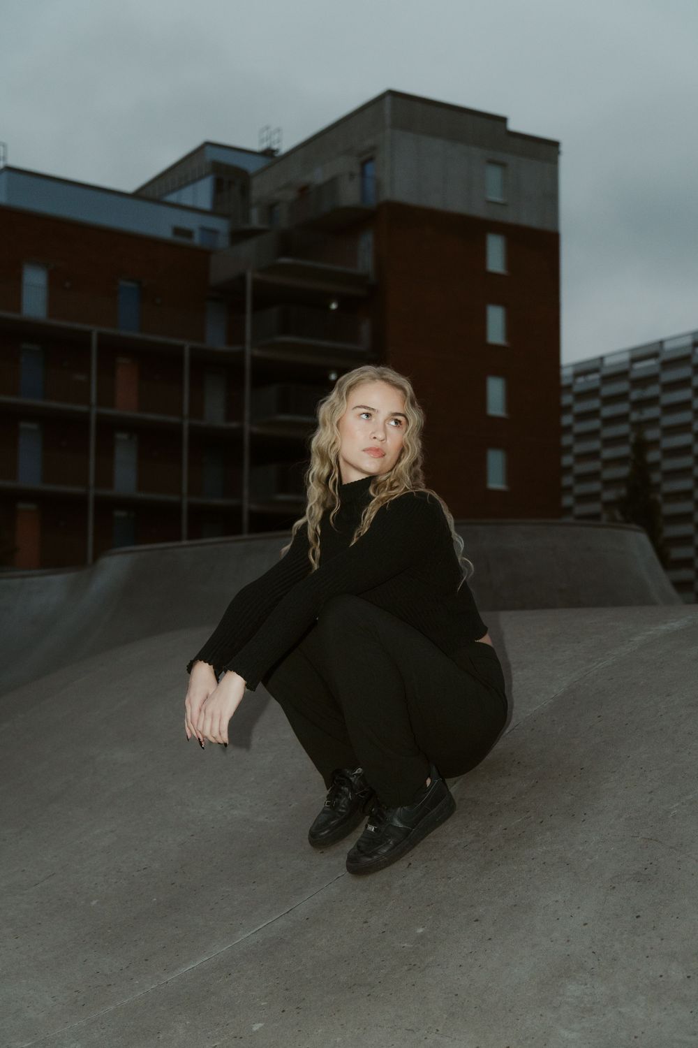 Moody urban photoshoot on concrete surface against brick building backdrop.