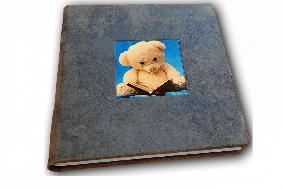 Gray photo album with vintage style binding lies on a flat surface with decorative photo corners showing on the cover.