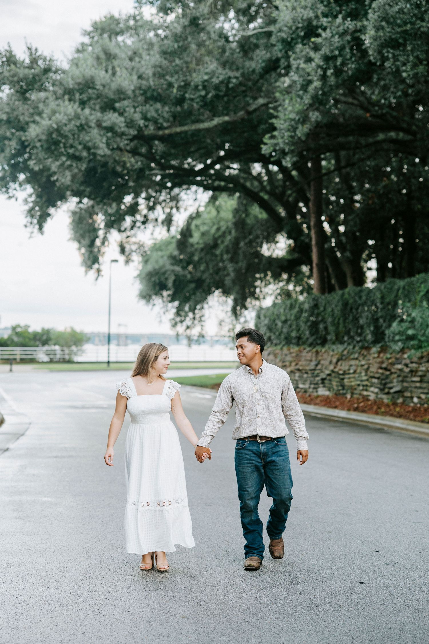 Several photos capture a couple strolling together on a peaceful stone-bordered pathway beneath large trees.