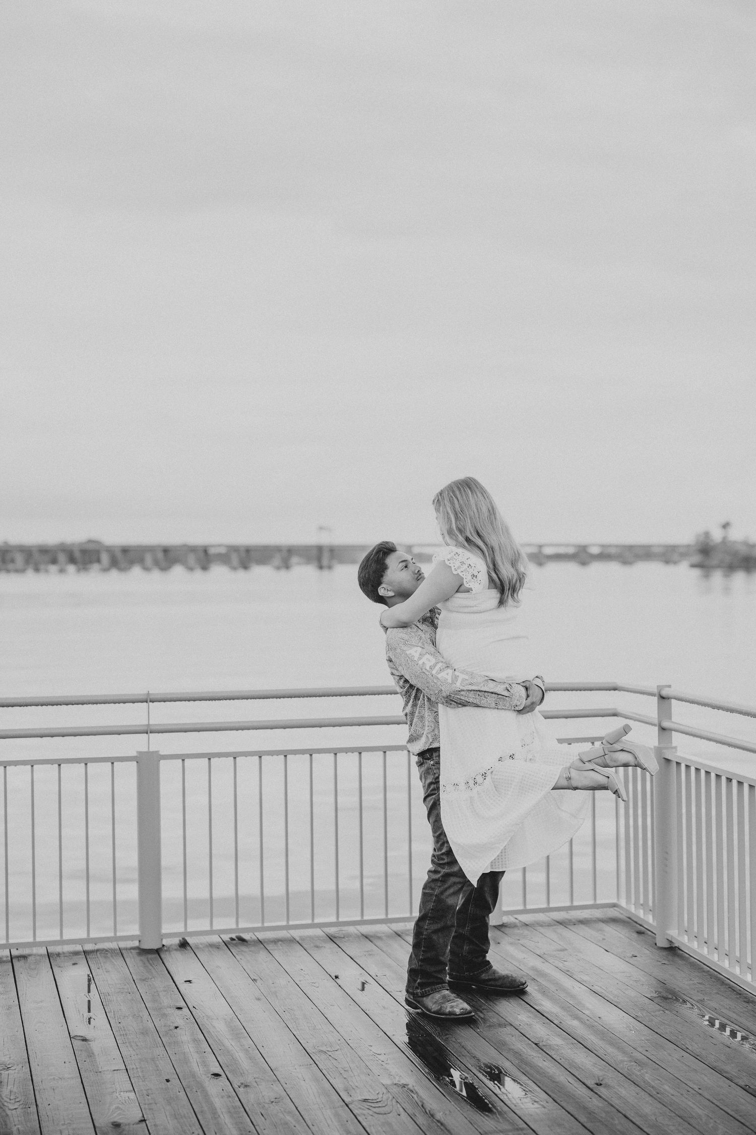 A romantic dance sequence unfolds on a wooden pier with a misty waterfront backdrop.
