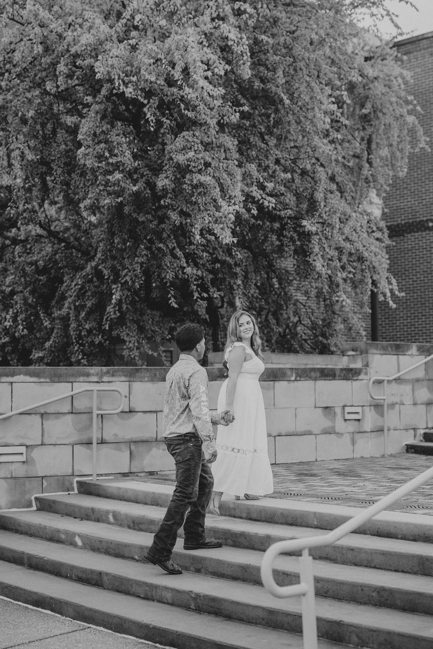 A series of black and white images showing two people playfully interacting on concrete steps.