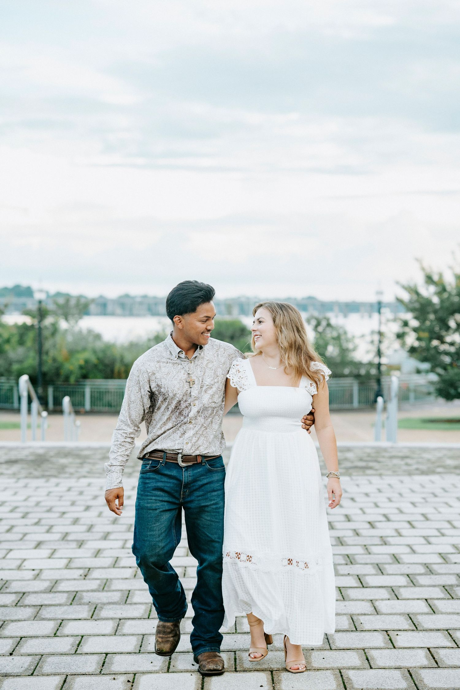 A couple dances and poses together on a decorative stone courtyard during an outdoor photoshoot.