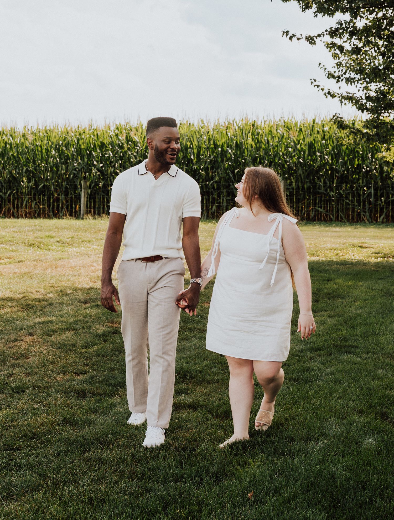 A couple walking hand in hand through a grassy field for Engagement Photoshoot at Waltz Vineyards Estate Winery in Manheim, P