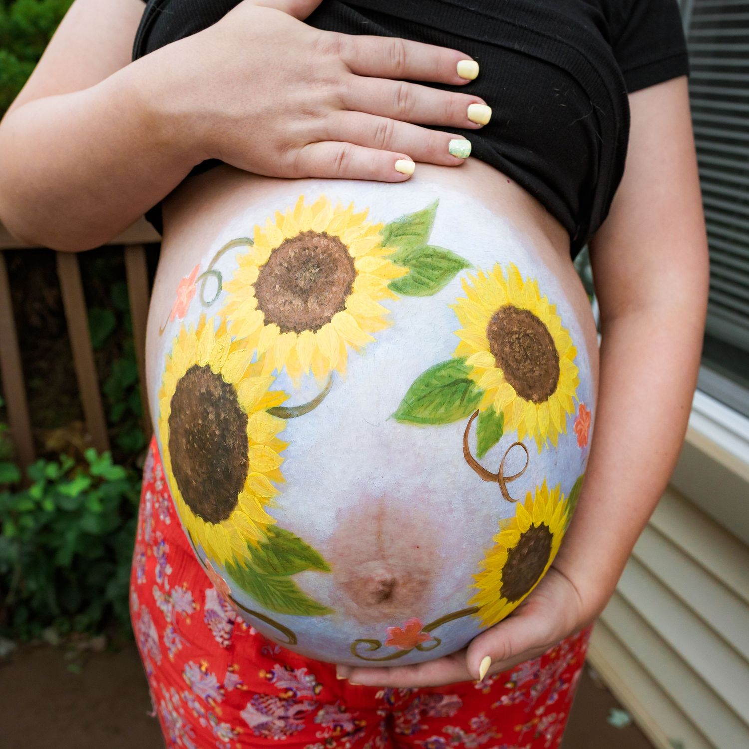 A pregnant belly painted with vibrant sunflowers and floral designs.