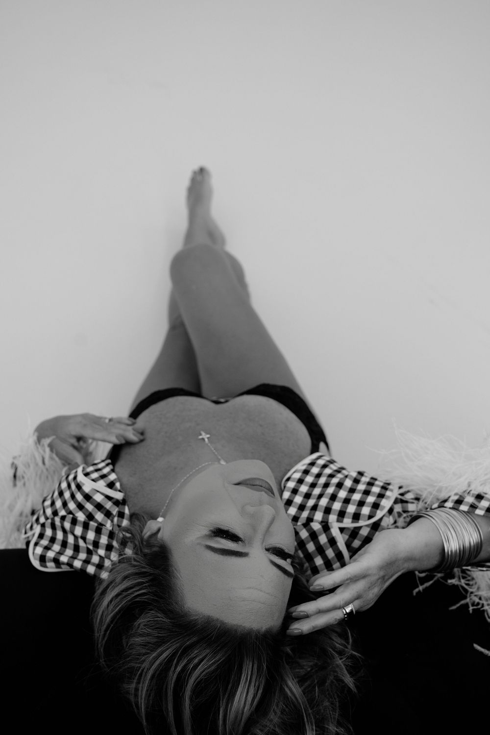 Black and white photo of someone reclining in gingham pattern clothing.