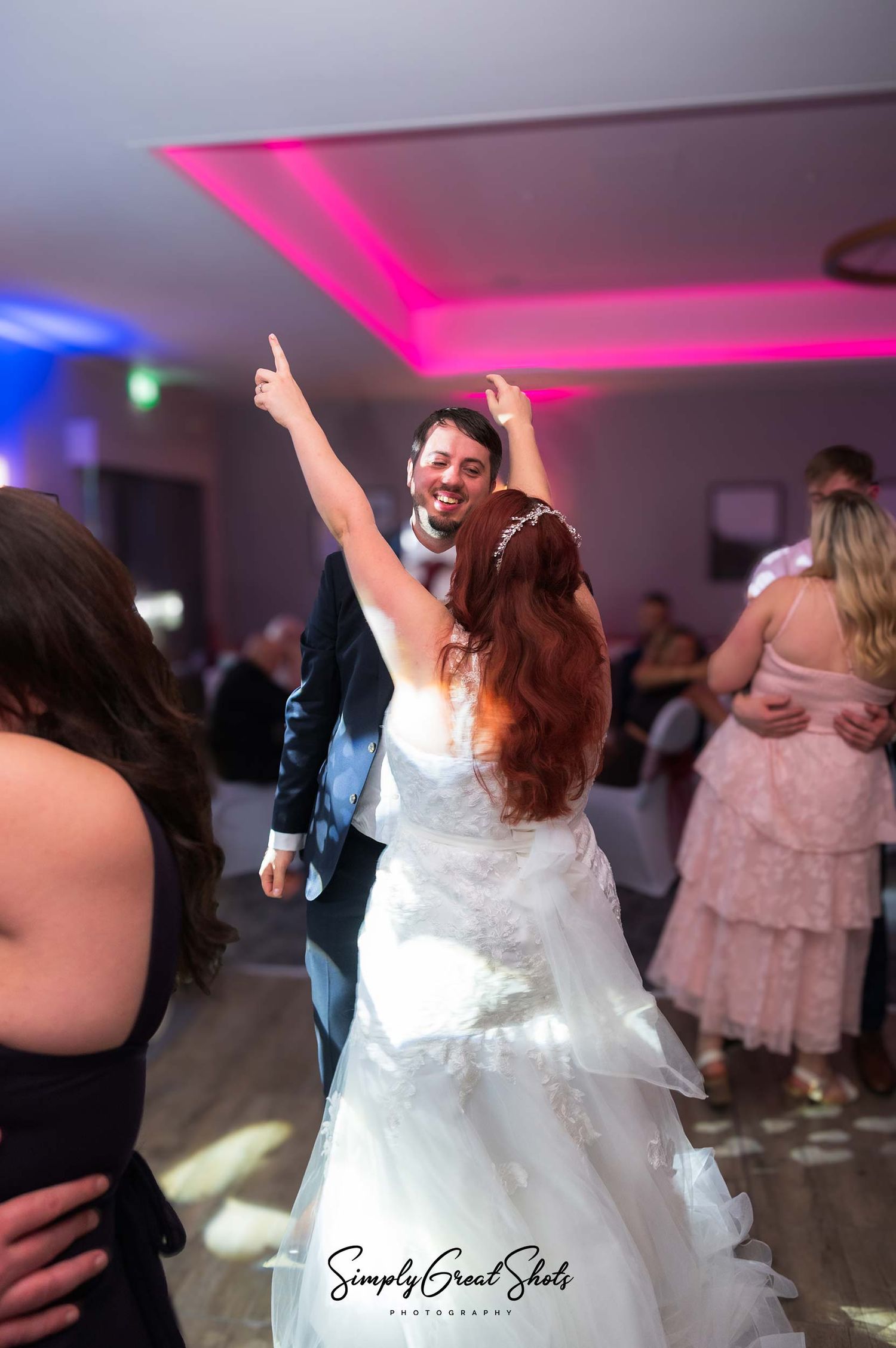 Eastwood hall wedding photographer captures a bride and groom dancing in the Chatterley suite with pink mood lighting