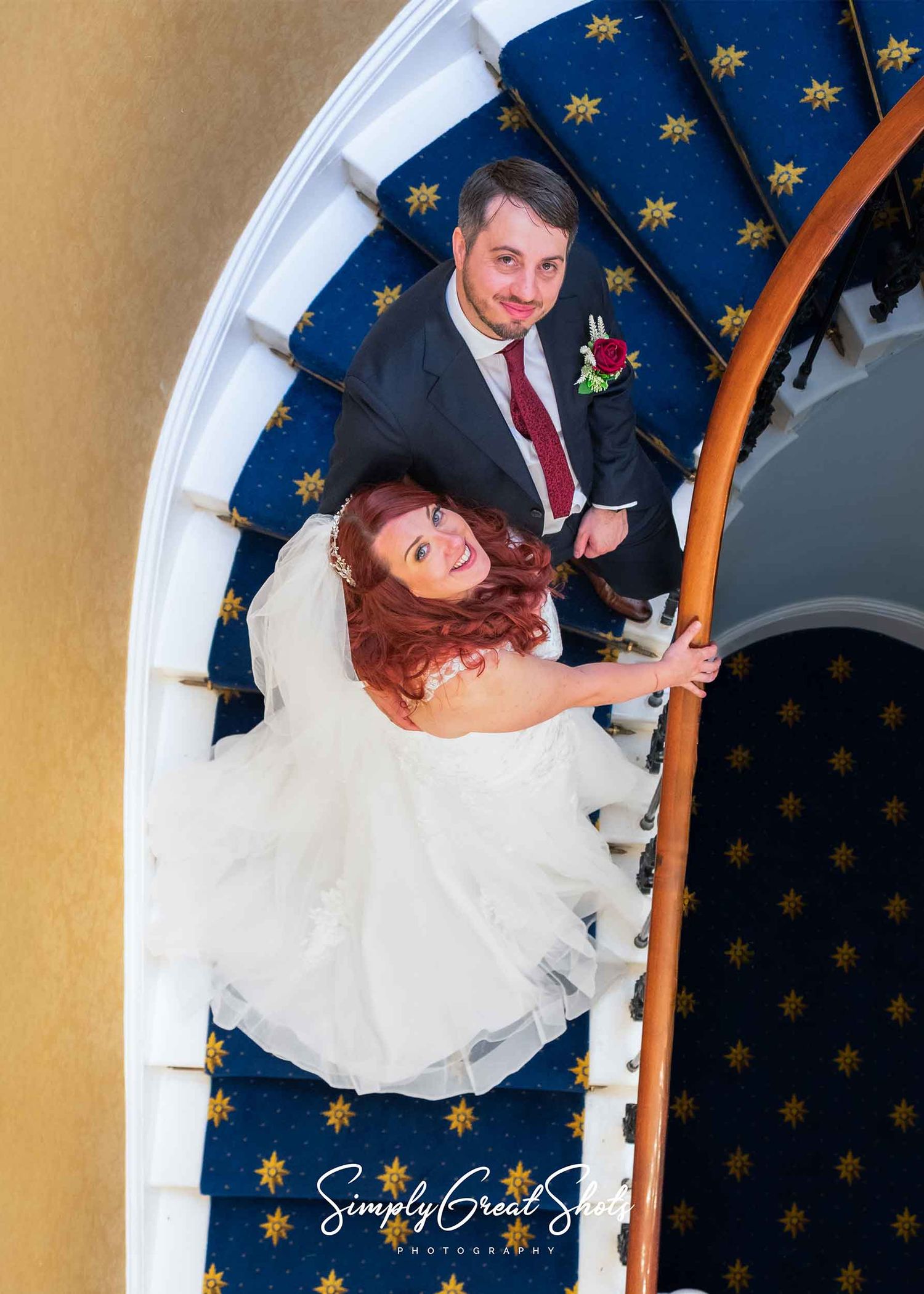 A bride and groom pose on the staircase in Eastwood hall, captured by a wedding photographer