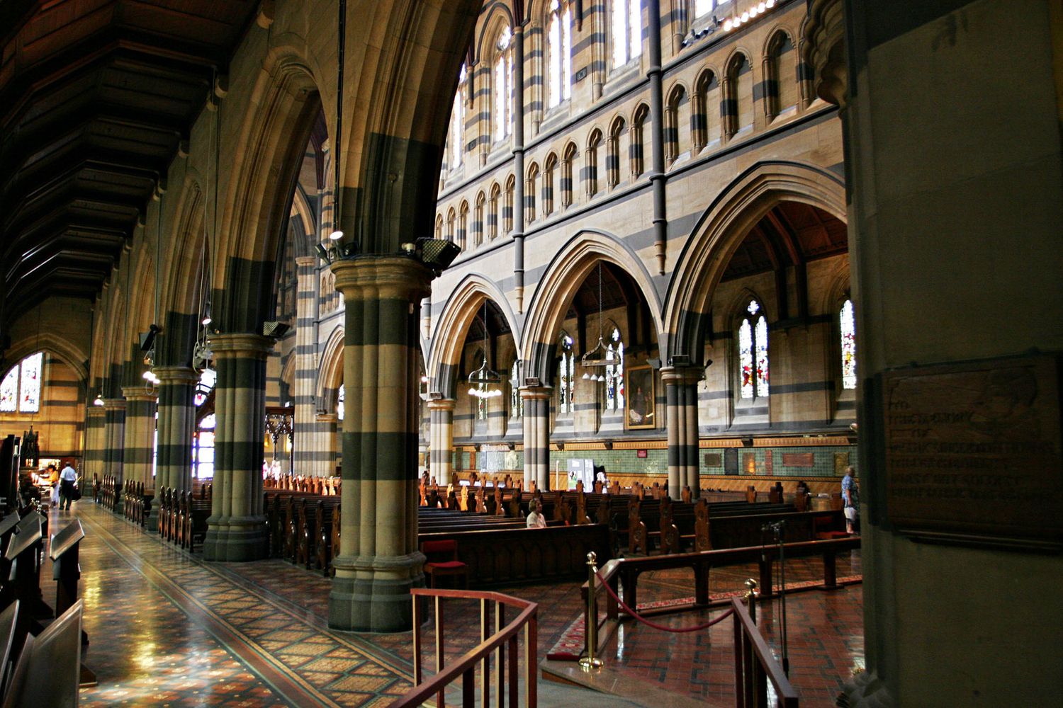 Interior view of historic Hamburg Town Hall showing ornate Gothic arches and columns with warm lighting in hallway.