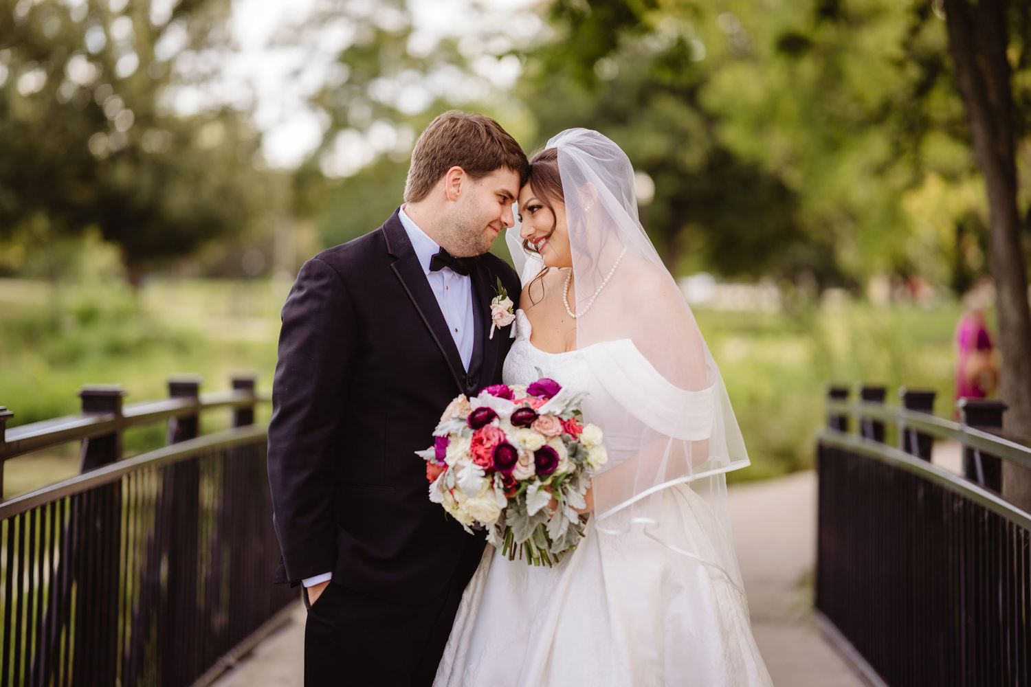 A wedding couple share intimate moments together on a wooden bridge in a romantic outdoor setting.