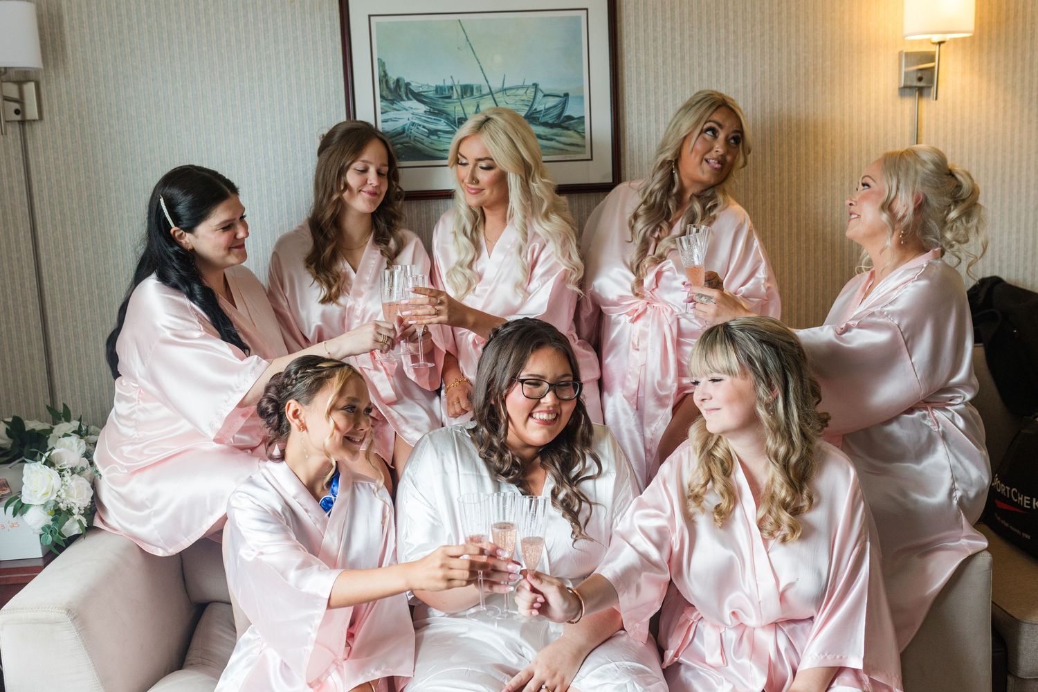 A group in matching pink and white striped robes celebrates joyfully together in a hotel room.