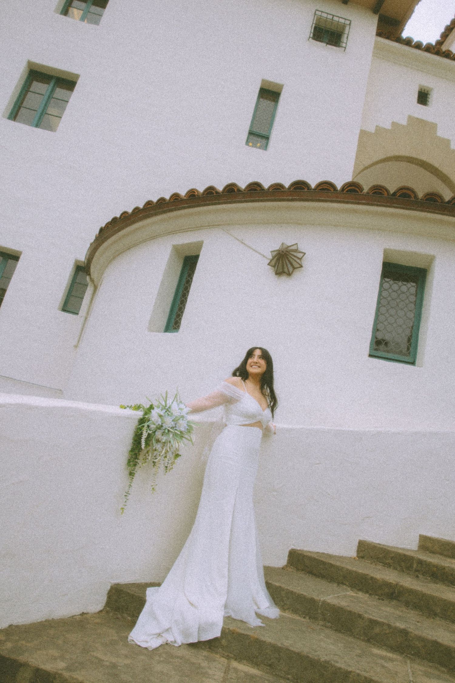A succession of artistic shots showing a person in a flowing white dress posing on stone steps near a white stucco building.