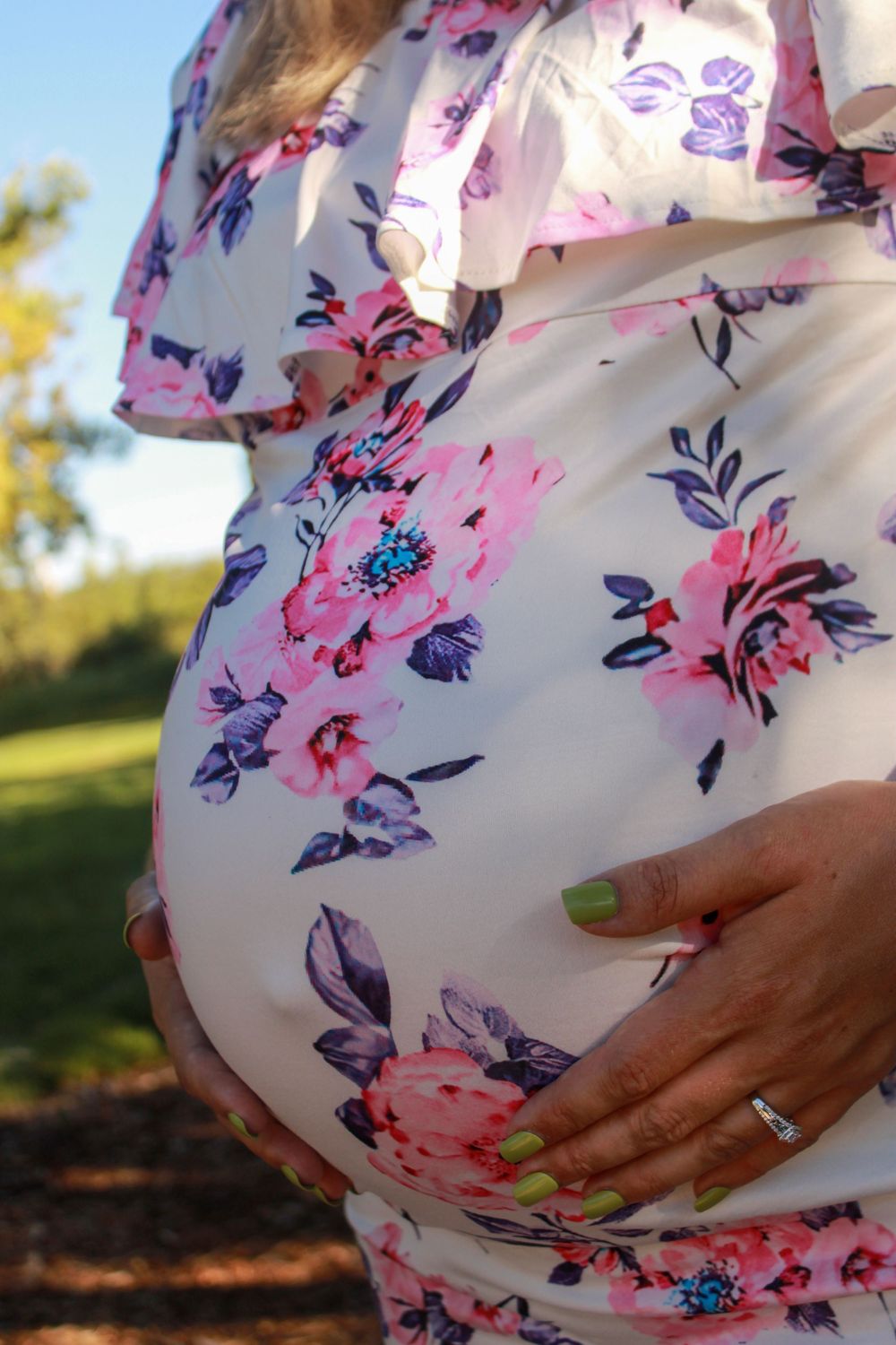Detail shots of a pregnant belly in a floral print maternity dress showing different angles in natural sunlight.