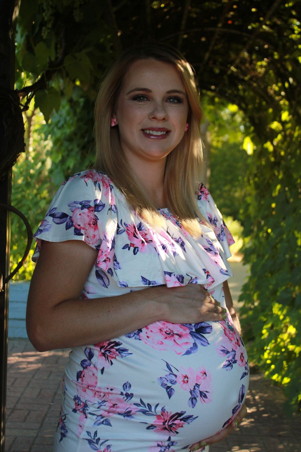 A floral dress photoshoot outdoors showing a springtime fashion look with pink and purple blooms on white fabric.