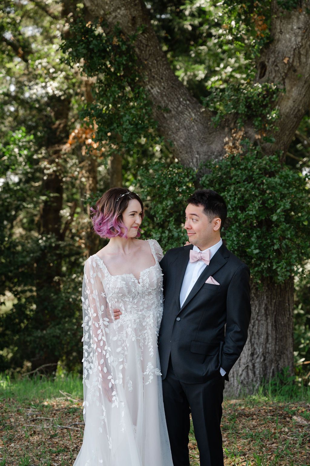 Romantic outdoor wedding photos with a couple in formal attire exchanging loving glances under lush green trees.
