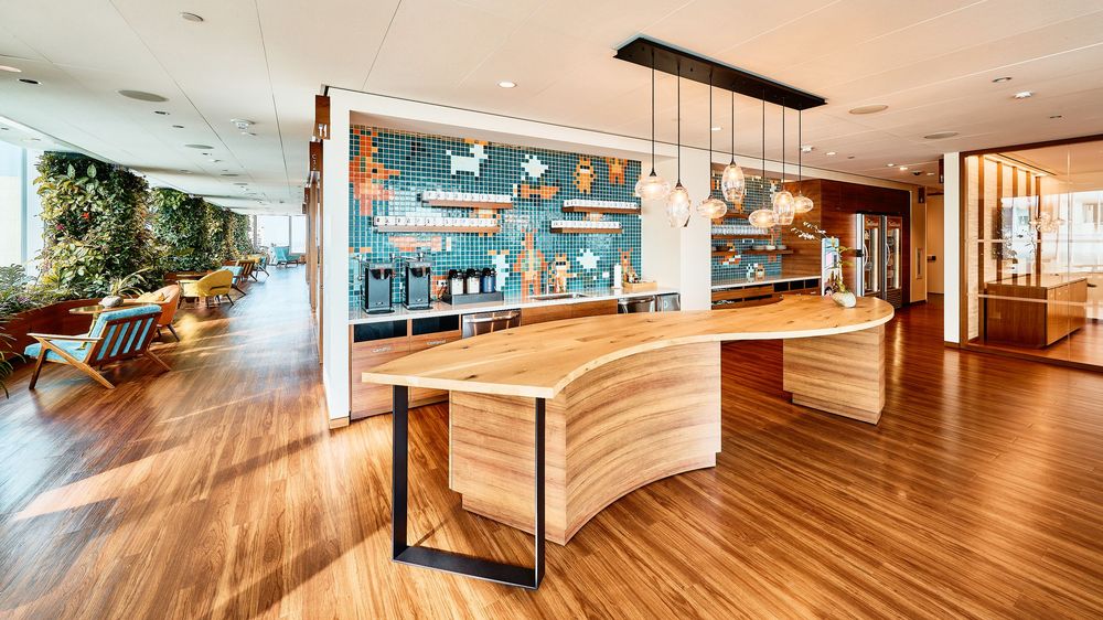 A panoramic view of modern interior spaces with polished hardwood floors and curved wooden wall features.