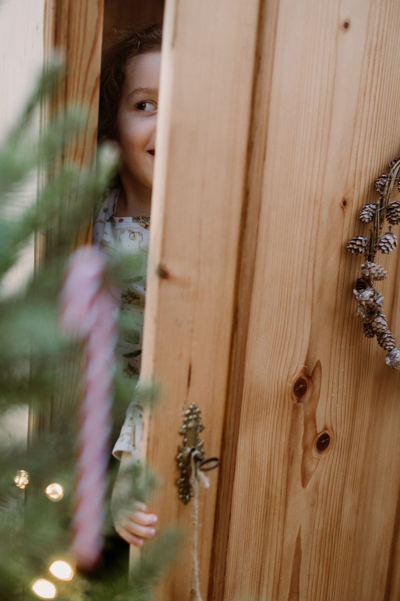 Someone wearing white mittens holds a wooden bowl filled with hazelnuts while standing on holiday-themed floor decorations.