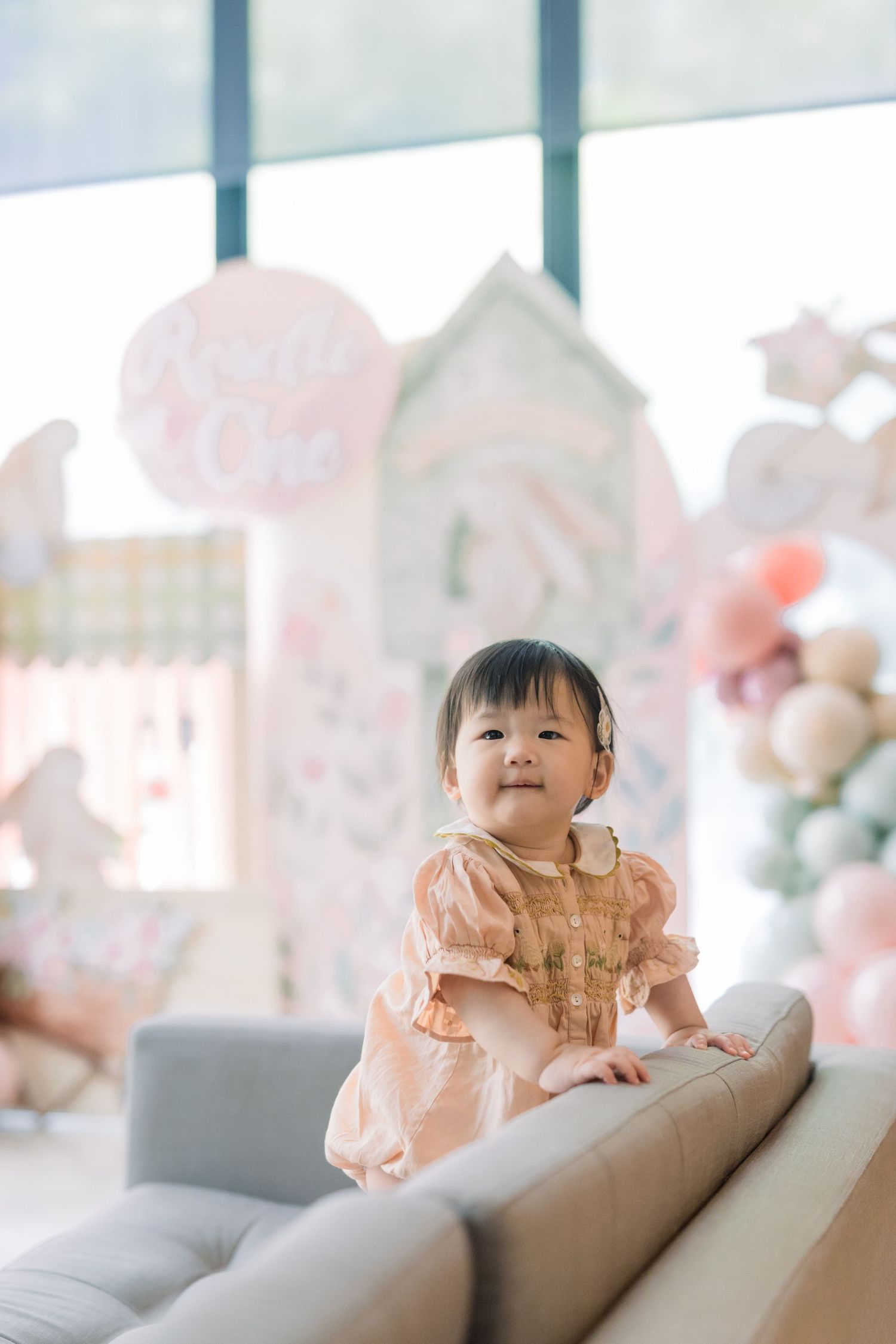Family sharing tender moments in front of a pink backdrop with floral decorations.