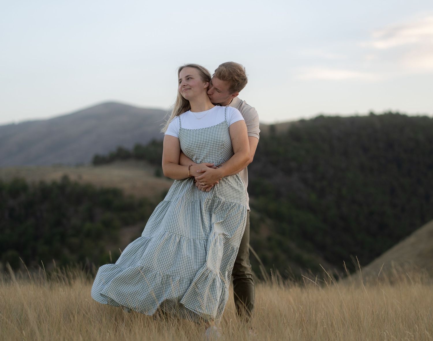 Smiling couple embracing during a golden hour engagement session in Logan, UT