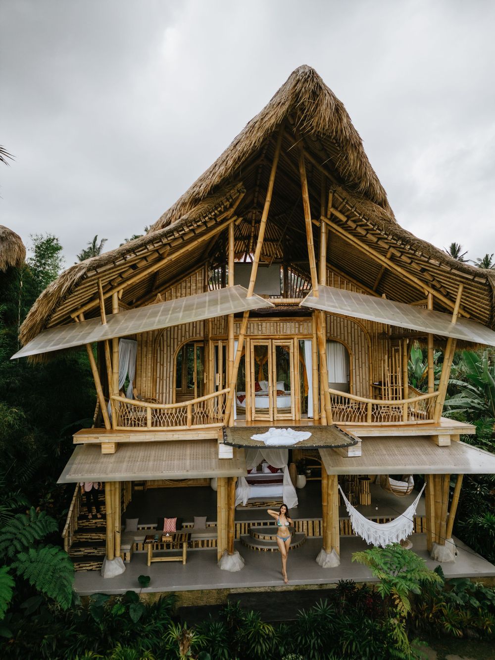 Architectural view of an eco-friendly bamboo house with distinctive A-frame design in tropical setting.