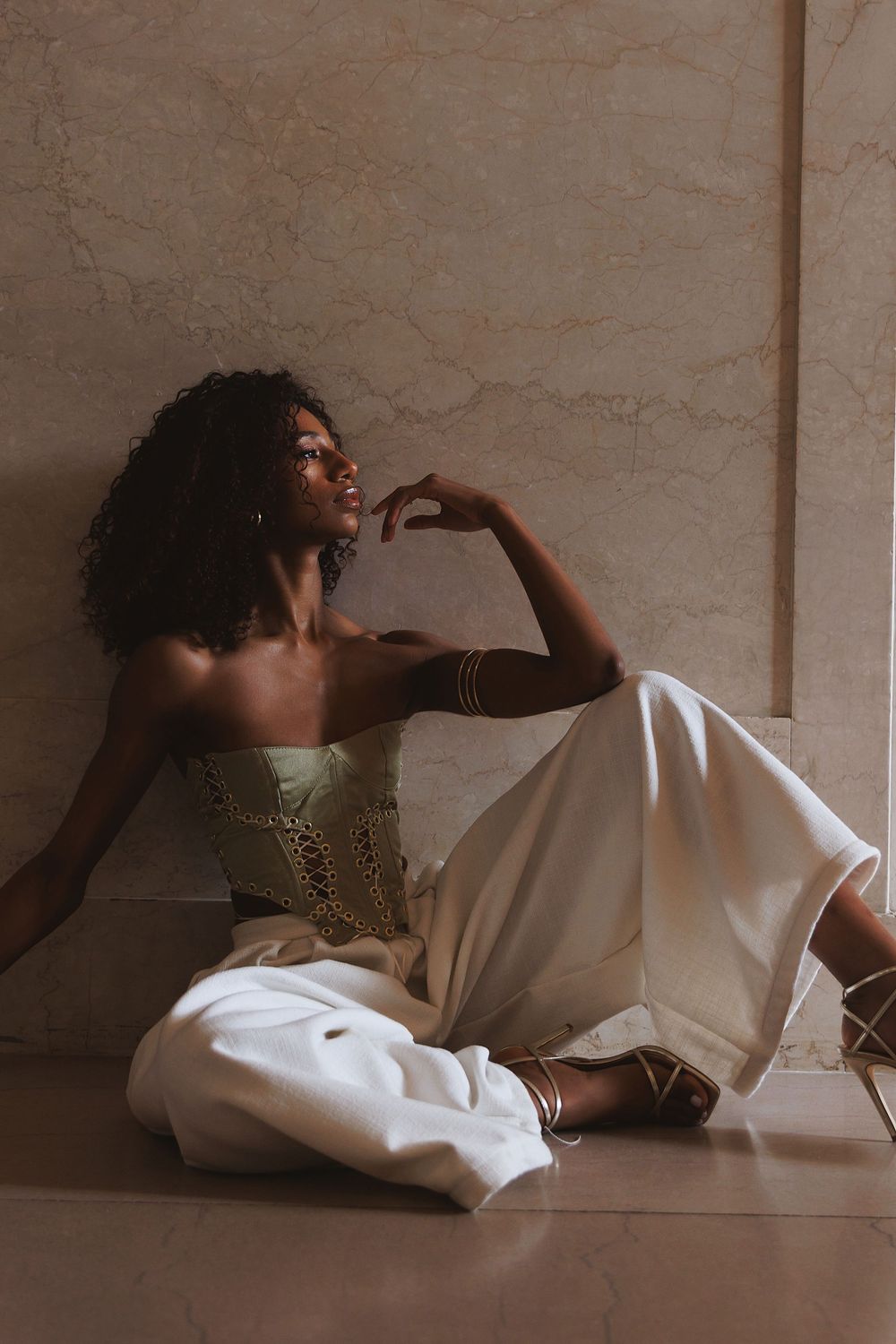 A cinematic series of images shows someone reclining in white fabric against a neutral wall with dramatic lighting.