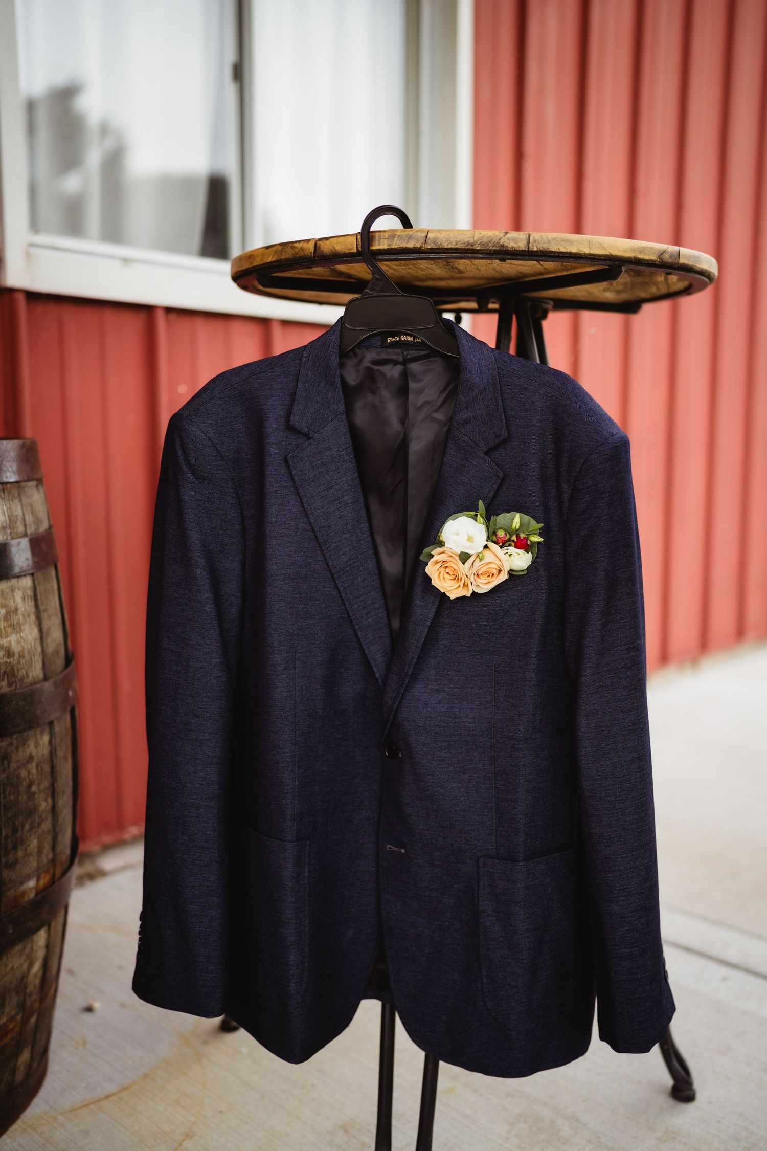 Navy blue suit jackets hanging on wooden hangers against a white wall with red siding.