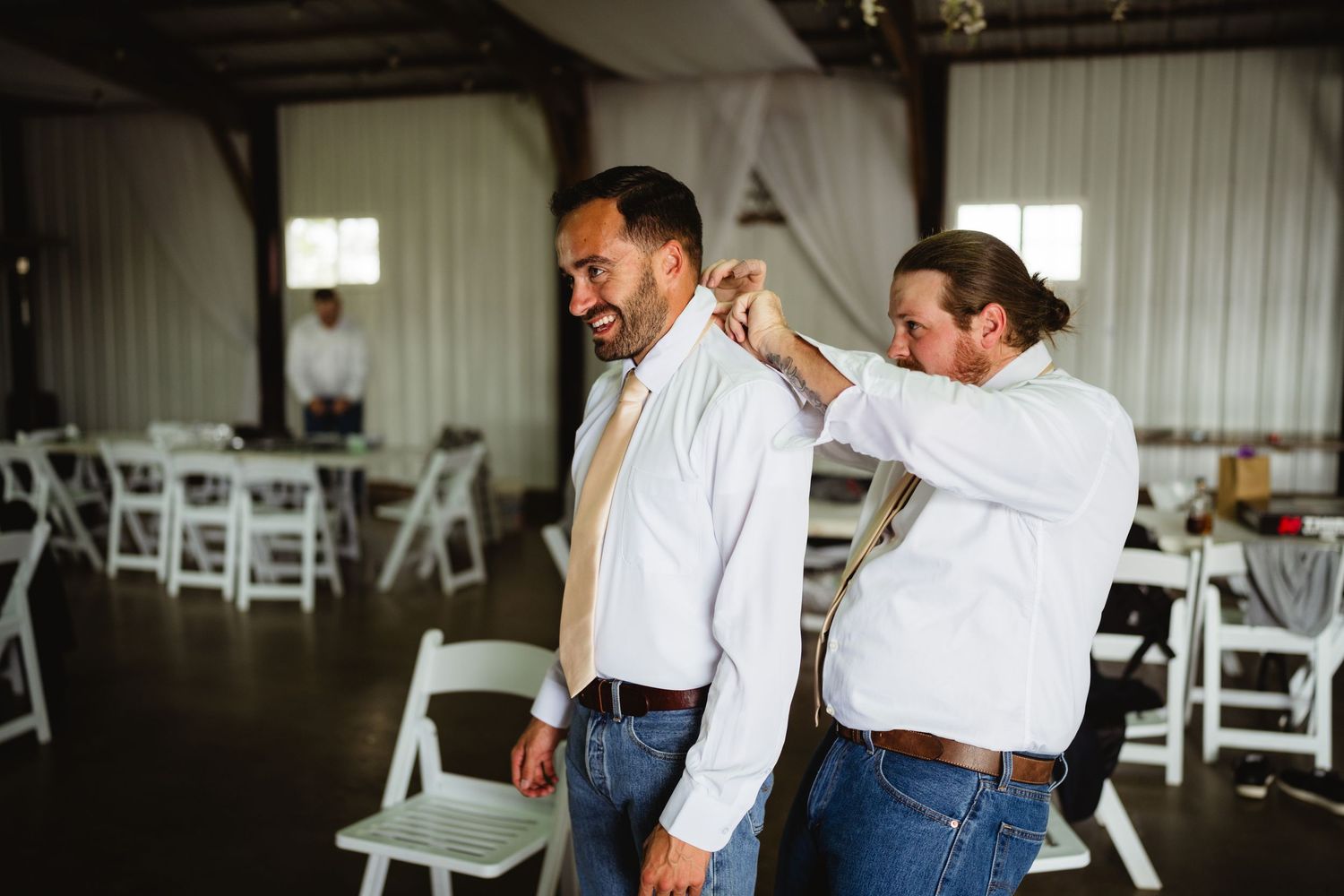 A couple in western attire dances together during a reception event inside a bright venue.