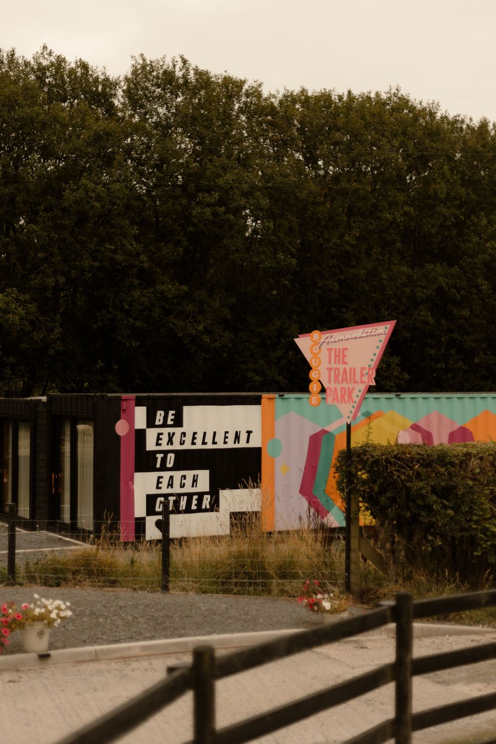 A series of vintage-style graphic signs with colorful text and block lettering displayed against a wooded background.