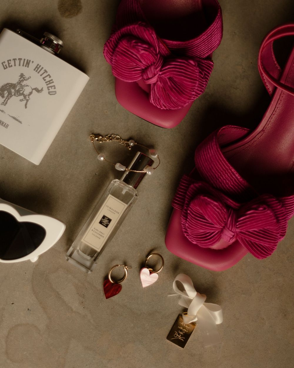 Pink rose petals lay scattered among metal keys and accessories in a moody, vintage-styled composition.