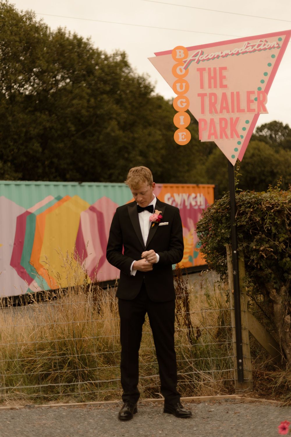Modern outdoor wedding photos feature colorful retro triangle signs as decorative backdrops in a rustic field setting.