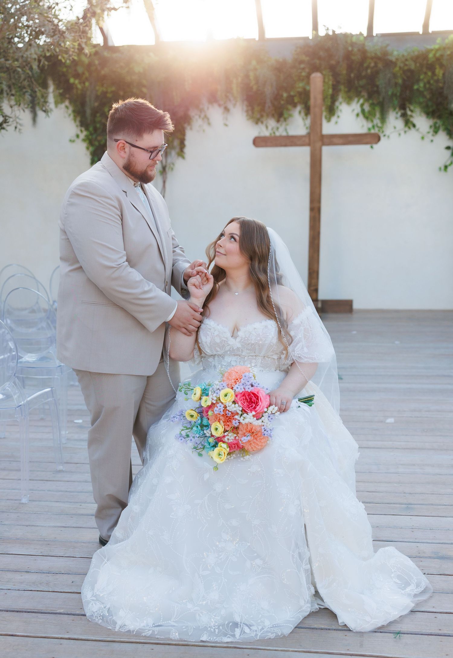 Romantic wedding couple sharing tender moments together on a wooden deck with pink and blue bouquet details at Greenhouse Two Rivers.