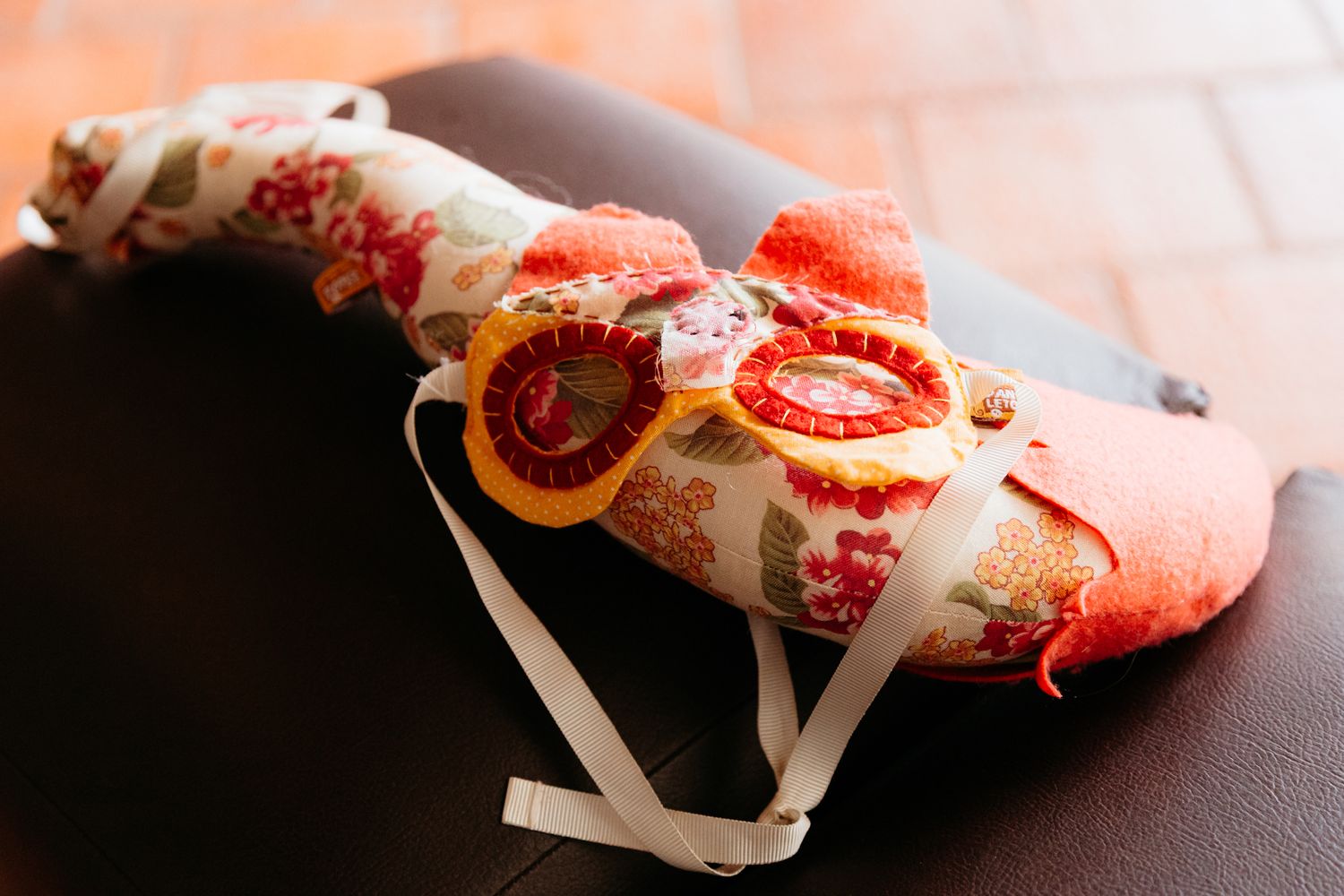 Red floral patterned cloth material wrapped around a curved stand on dark surface.