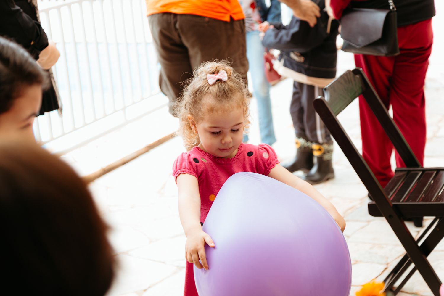 Young children playing with colorful balloons during a festive party with party decor and activity tables.