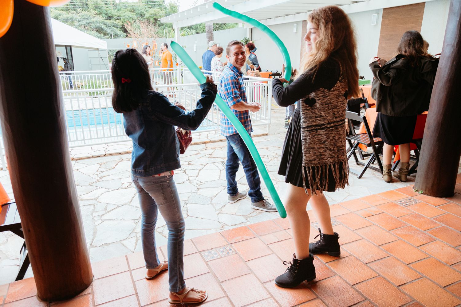 A group of people standing in line at a covered outdoor event area with orange tile flooring.