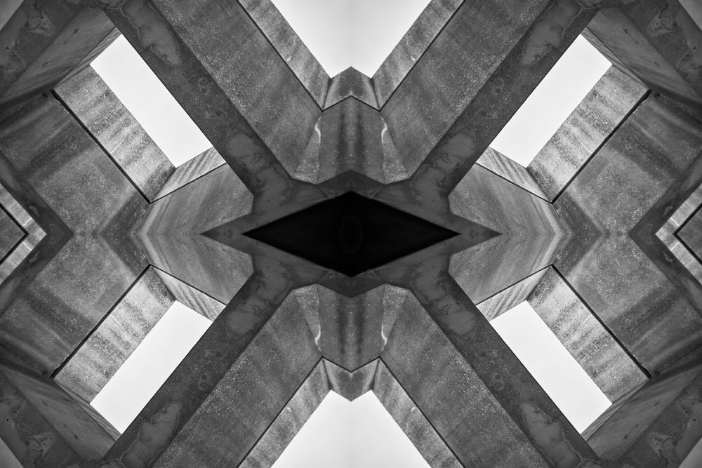 Abstract architectural pattern of concrete beams forming symmetrical X shape in black and white photography.