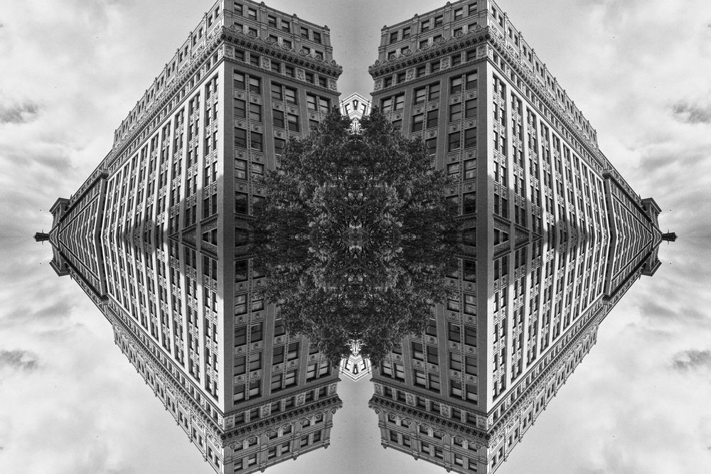 Mirrored architectural photograph creates symmetrical pattern of tall urban building against cloudy sky.