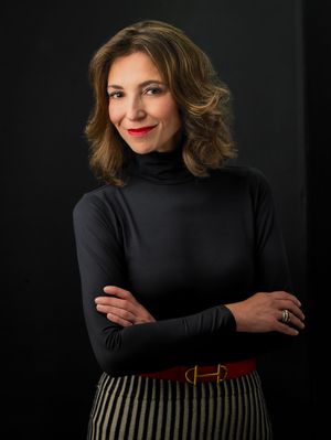 Professional portrait of woman in black turtleneck and striped skirt.