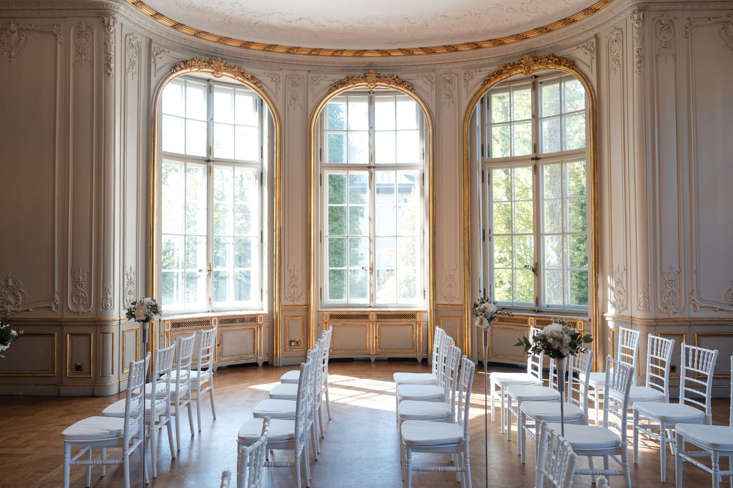 Bright classical room with arched windows and white chairs arranged for an elegant ceremony. Organized wedding by MyCastleWedding | Dresden.