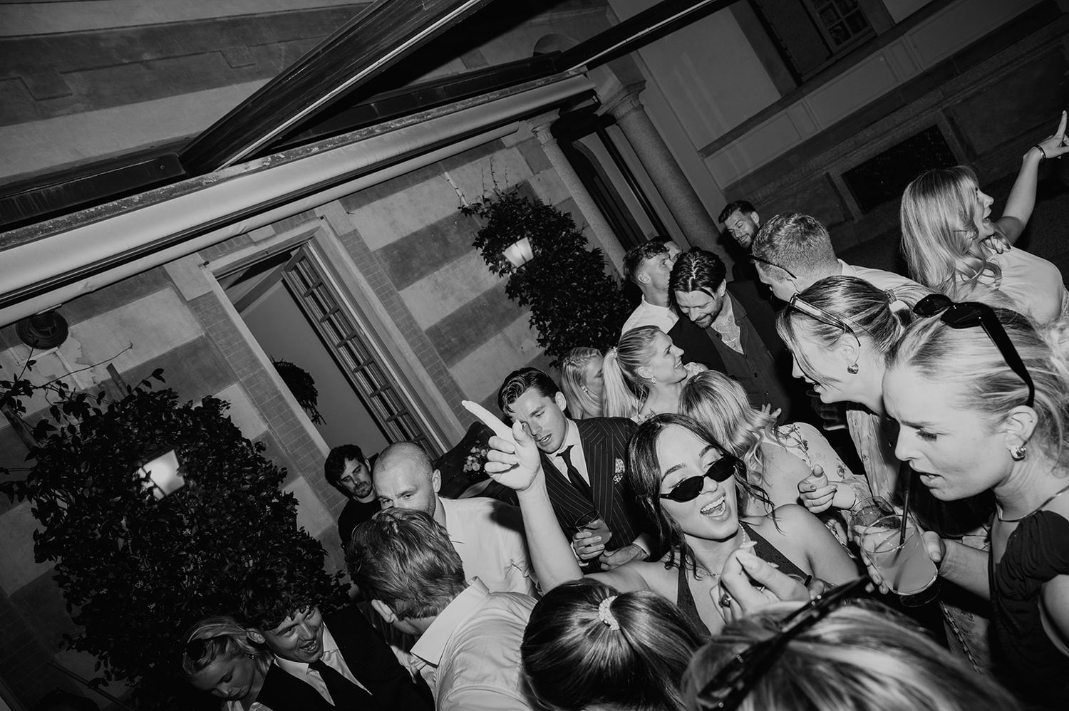 Black and white photo of a crowded nightclub or party with people dancing and socializing in close quarters.