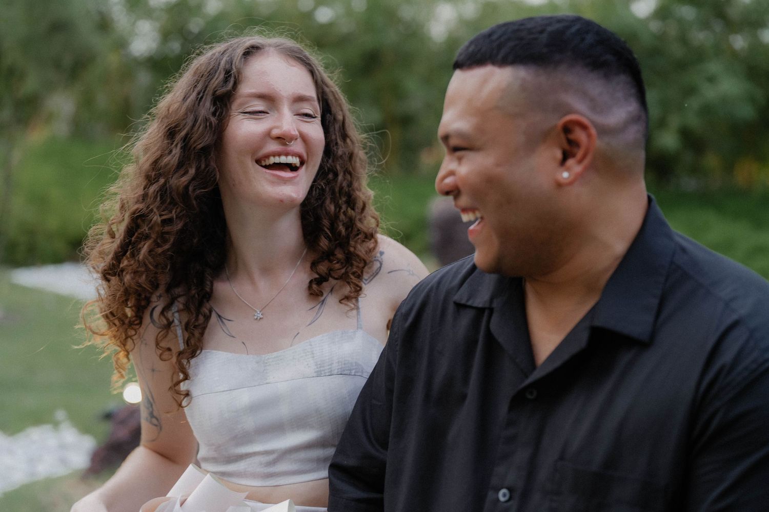 A candid moment of shared laughter in an outdoor garden setting.