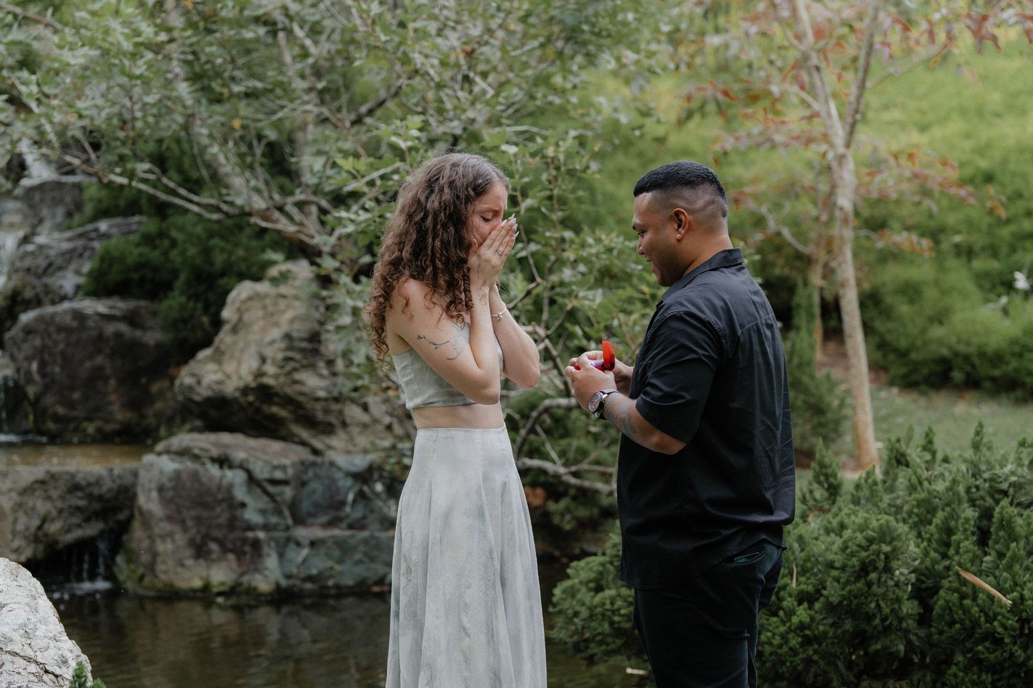 Romantic moments captured by a small waterfall in a lush garden setting.