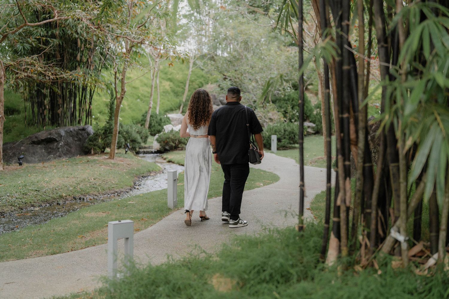 Walking through a tropical garden pathway lined with bamboo and palm trees.